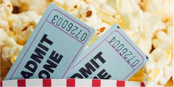 A pair of movie tickets with popcorn behind them.